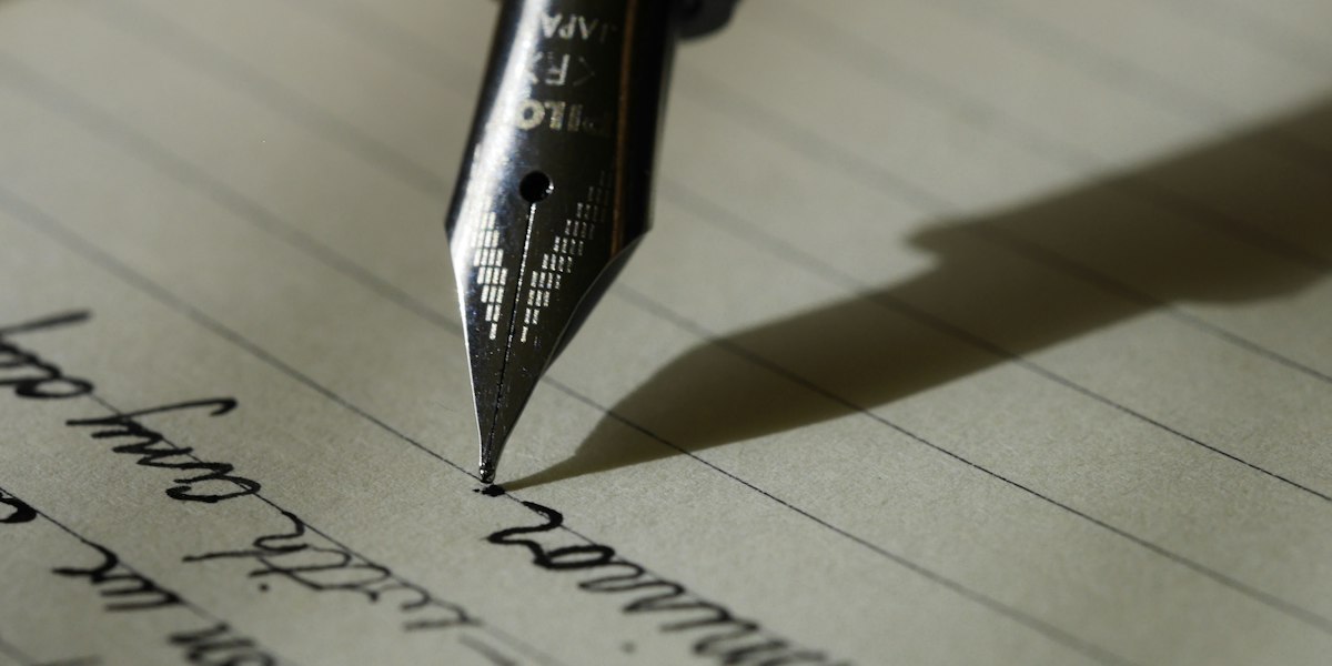 Person writing in a journal by a window with no phone in sight