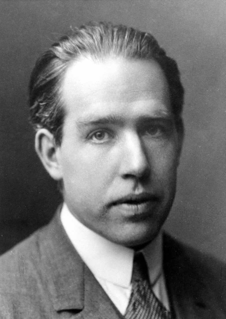 Black-and-white portrait of Niels Bohr in a suit and tie, his face turned toward the camera